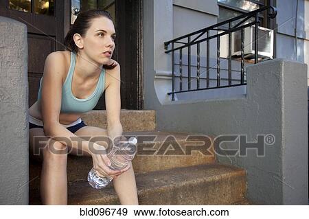 Caucasian woman relaxing with water bottle after exercise View Large Photo Image Stock Photo - Caucasian woman relaxing with water bottle after exercise. Fotosearch