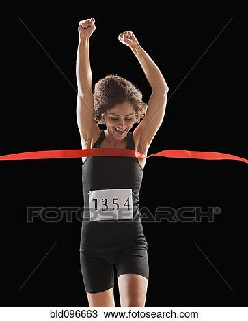 Stock Image - Caucasian woman running across race finish line. Fotosearch
