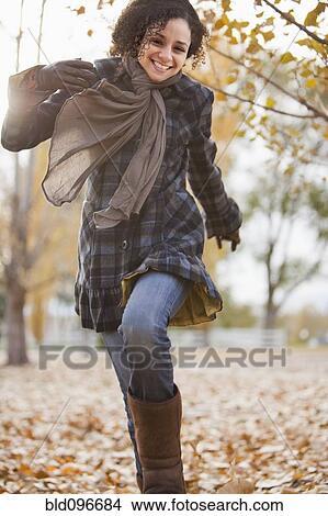 Picture - Caucasian woman running in autumn leaves. Fotosearch