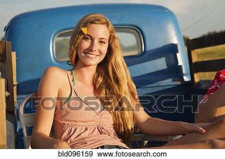 Stock Photo - Caucasian woman sitting in back of truck. Fotosearch