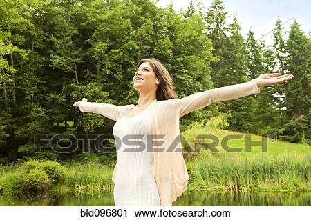 Stock Image - Caucasian woman standing outdoors with arms outstretched. Fotosearch