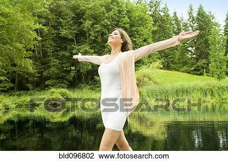 Stock Image - Caucasian woman standing outdoors with arms outstretched. Fotosearch