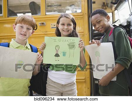 Picture - Children holding drawings near school bus. Fotosearch
