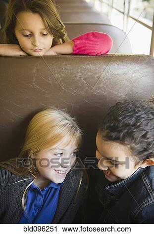 Stock Image - Children riding on school bus. Fotosearch
