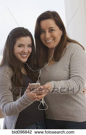 Stock Image - Chilean mother and daughter listening to mp3 player. Fotosearch