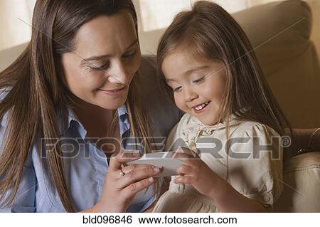 Stock Photograph - Chilean mother showing cell phone to daughter. Fotosearch