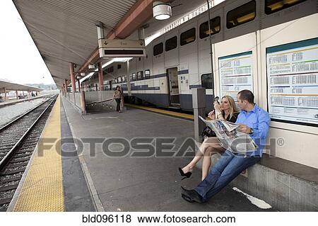 Couple sitting on train platform waiting for train View Large Photo Image Stock Photo - Couple sitting on train platform waiting for train. Fotosearch