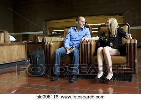 Stock Photograph - Couple sitting together in train station. Fotosearch
