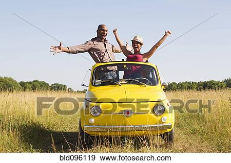 Couple standing in car sun roof in field View Large Photo Image Stock Photo - Couple standing in car sun roof in field. Fotosearch