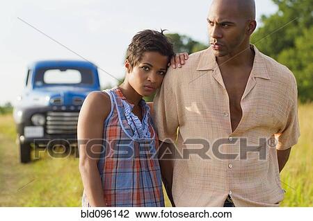 Stock Image - Couple standing outdoors near truck. Fotosearch