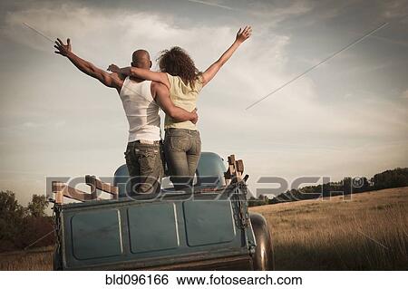 Stock Photograph - Couple standing together in back of old-fashioned truck. Fotosearch