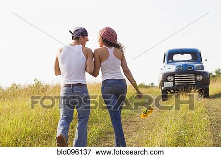 Stock Photo - Couple walking in field near truck. Fotosearch