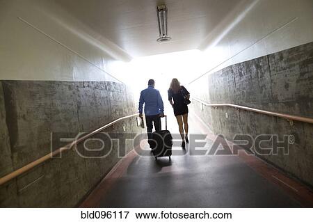 Stock Photo - Couple walking with luggage in tunnel. Fotosearch