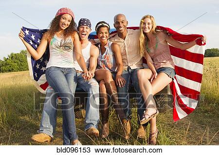 Stock Image - Friends holding American flag on back of truck. Fotosearch