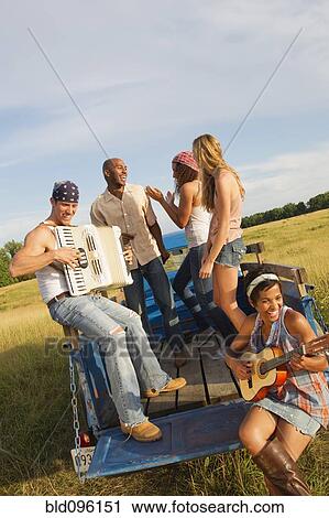 Stock Image - Friends playing musical instruments on back of truck. Fotosearch