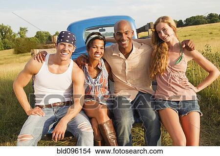 Picture - Friends sitting together on back of truck. Fotosearch