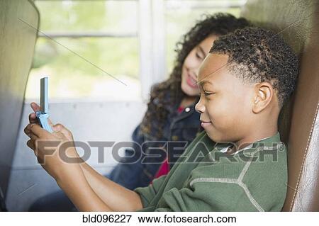 Girl watching boy playing video game on school bus View Large Photo Image Stock Photo - Girl watching boy playing video game on school bus. Fotosearch