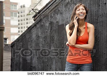 Grinning mixed race woman talking on cell phone outdoors View Large Photo Image Stock Photo - Grinning mixed race woman talking on cell phone outdoors. Fotosearch