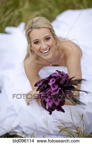 Picture - Hispanic bride holding bouquet of flowers. Fotosearch