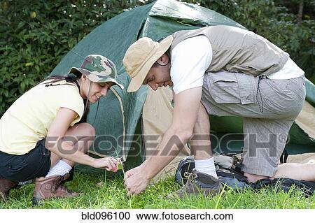 Stock Image - Hispanic couple setting up tent together. Fotosearch