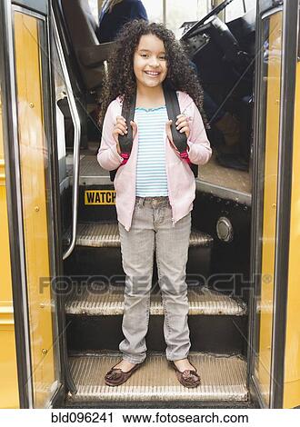 Stock Image - Hispanic girl getting onto school bus. Fotosearch