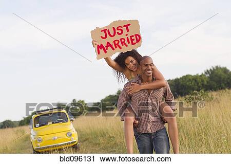 Man piggybacking wife who is holding just married sign View Large Photo Image Stock Image - Man piggybacking wife who is holding just married sign. Fotosearch