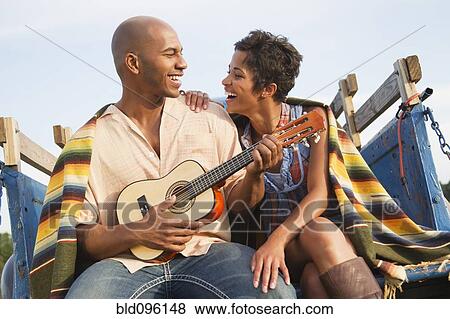 Man playing ukulele for wife on back of truck View Large Photo Image Stock Photo - Man playing ukulele for wife on back of truck. Fotosearch