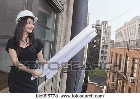 Stock Photo - Mixed race businesswoman holding blueprints. Fotosearch