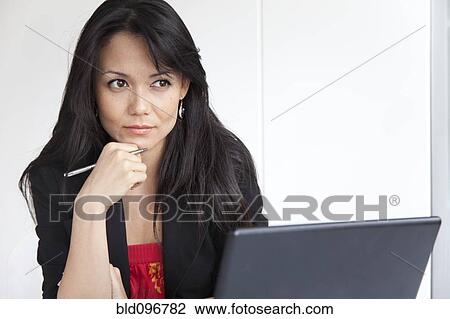 Stock Image - Mixed race businesswoman sitting with laptop. Fotosearch
