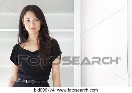 Picture - Mixed race businesswoman standing in office. Fotosearch