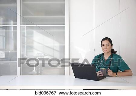 Stock Photo - Mixed race doctor using laptop. Fotosearch