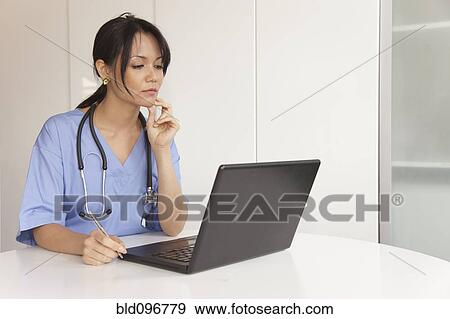 Stock Photo - Mixed race doctor using laptop. Fotosearch