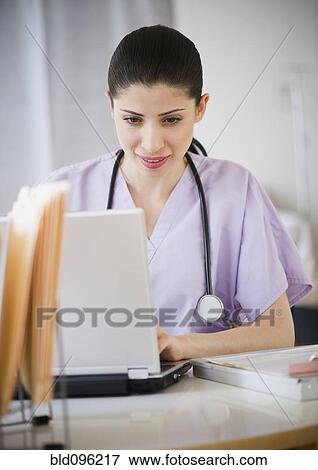 Stock Photo - Mixed race nurse using laptop in hospital. Fotosearch