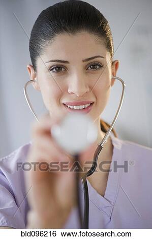 Stock Photograph - Mixed race nurse using stethoscope. Fotosearch