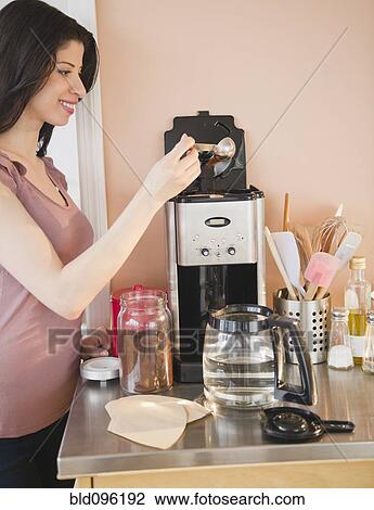 Stock Image - Mixed race woman making coffee. Fotosearch