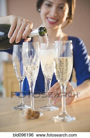 Mixed race woman pouring Champagne into glasses View Large Photo Image Stock Photograph - Mixed race woman pouring Champagne into glasses. Fotosearch
