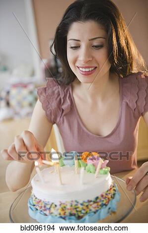 Picture - Mixed race woman preparing birthday cake. Fotosearch