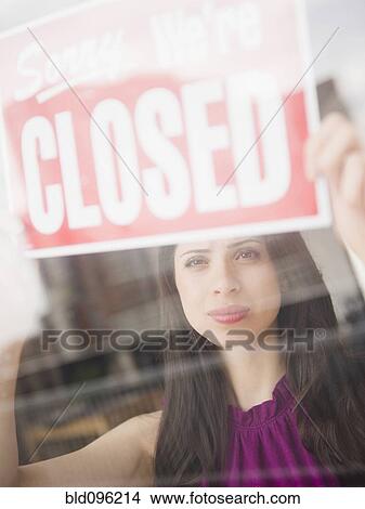 Picture - Mixed race woman putting up closed sign. Fotosearch