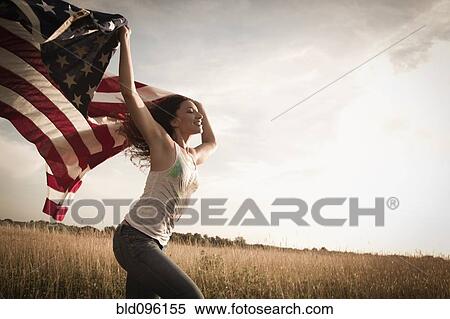 Stock Photography - Mixed race woman running in field with American flag. Fotosearch