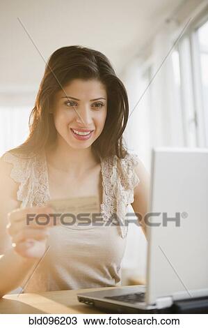 Stock Image - Mixed race woman shopping online with credit card. Fotosearch