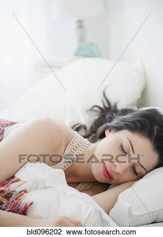 Stock Image - Mixed race woman sleeping in bed. Fotosearch