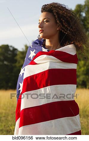 Stock Photograph - Mixed race woman wrapped in American flag. Fotosearch