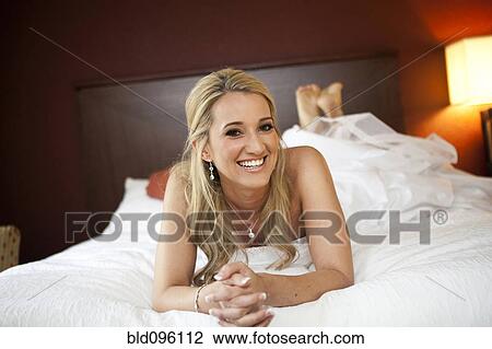 Stock Image - Smiling Hispanic woman laying in bed. Fotosearch