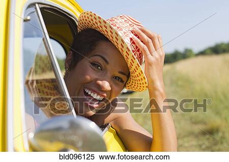 Stock Photography - Smiling mixed race woman leaning out of car window. Fotosearch