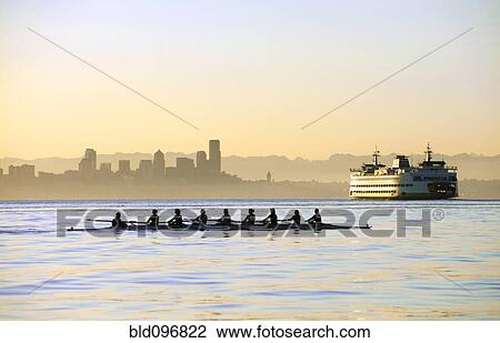 Stock Image - Team rowing boat in bay. Fotosearch