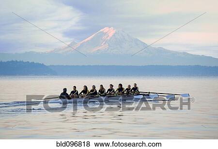 Stock Photo - Team rowing boat in bay. Fotosearch