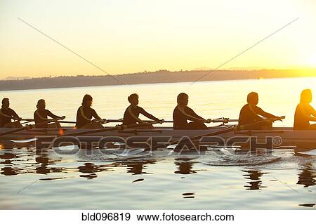 Stock Photo - Team rowing boat in bay. Fotosearch