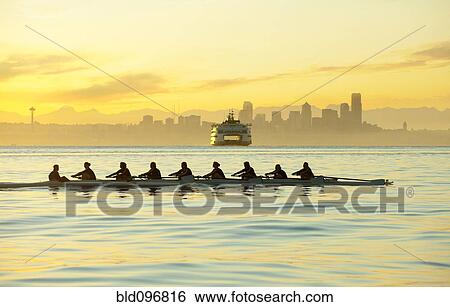 Stock Photograph - Team rowing boat in bay. Fotosearch