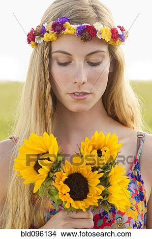 Picture - Tranquil Caucasian woman holding sunflowers. Fotosearch