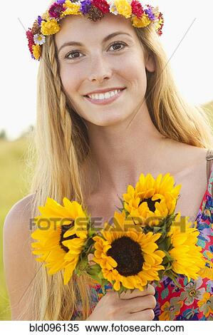 Stock Photography - Tranquil Caucasian woman holding sunflowers. Fotosearch